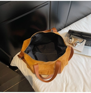 Detalle del bolso tote amarillo con asas de cuero marrón y bolsillo interior con cremallera