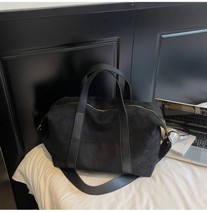 Detalle del bolso de viaje de ante negro con correas de cuero y cremallera dorada