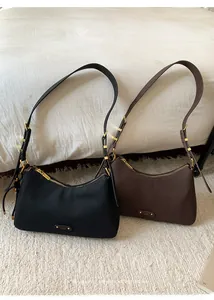 Detailed view of crescent shoulder bags in black and dark brown with gold metal accents