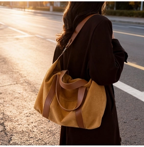 Primer plano de bolso tote de ante jengibre con asas de cuero marrón bajo luz de atardecer
