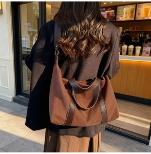 Bolso tote de ante marrón oscuro con correas de cuero en una escena de café cálida