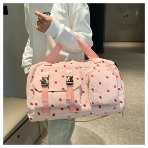 Detailed look at strawberry print corduroy travel bag with buckles on female model
