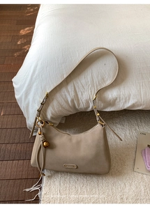 Detail of beige half-moon shoulder bag with golden buckle and sleek matte leather finish