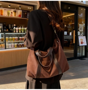 Primer plano de un gran bolso tote de ante marrón con asas de cuero en una cafetería acogedora