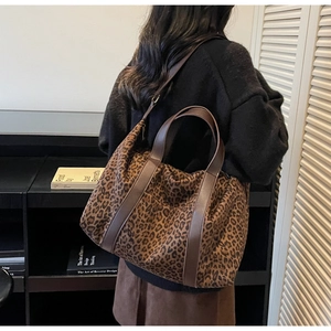 Detail of leopard print tote bag with brown leather straps worn by model for daily commute