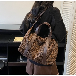 Detailed view of leopard print canvas tote bag with leather straps on model shoulder