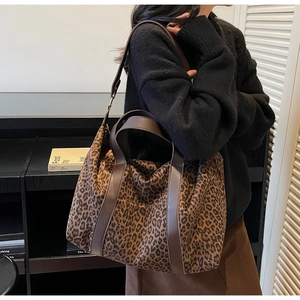 Close-up of leopard print tote bag with brown leather handles worn by a fashion model