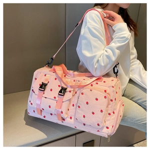 Detail of pink strawberry corduroy travel bag showing side pockets and buckles