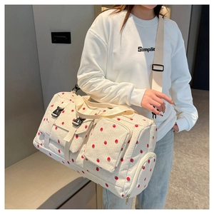 Detailed view of canvas travel bag with strawberry print and buckle pockets