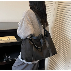 Close-up of black tote bag with leather straps and wide shoulder strap for commuting
