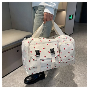 Detail of large travel bag with red strawberry pattern and functional buckle pockets