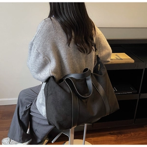 Detalle del bolso tote negro grande con textura mate y asas de cuero liso suaves