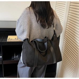 Detalle de un gran bolso tote negro con asas largas llevado al hombro en un estilo casual