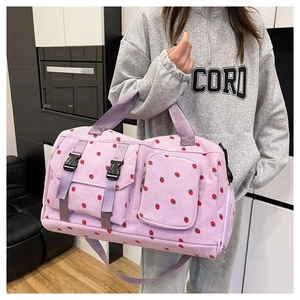 Detail of light purple corduroy travel bag with red strawberry print and buckle