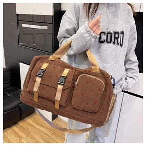 Detail of brown corduroy travel bag with red dots and buckled pockets showing fabric texture
