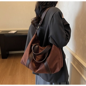 Vista detallada de un bolso tote de ante café llevado por una modelo en un interior