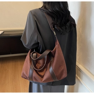 Detalle del bolso tote de ante marrón rojizo sobre una chaqueta para el estilo de oficina