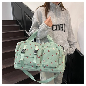 Detail of mint green corduroy travel bag with strawberry print and functional pockets