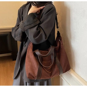 Close-up of deep brown suede tote bag featuring leather handles and adjustable shoulder strap