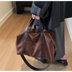 Detalle macro del bolso tote grande de ante café oscuro con correas de cuero y hebilla