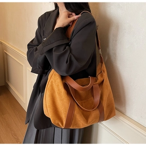 Modelo luciendo un bolso tote grande de ante jengibre con correas de cuero marrón y bandolera