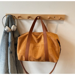 Bolso de ante ocre colgado en un perchero de madera con chaqueta vaquera y cascos
