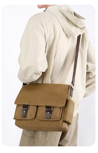 Detailed view of brown canvas messenger bag featuring vintage leather straps and metal rivets