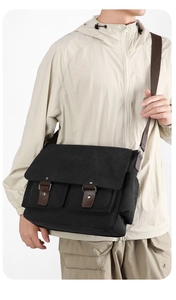 Close-up of black canvas messenger bag featuring brown leather straps and adjustable strap