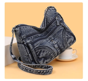 Dettaglio della borsa a tracolla in denim blu lavato con tasche multiple e zip metalliche