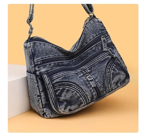 Dettaglio della borsa a tracolla in denim blu lavato con cerniere e tracolla regolabile