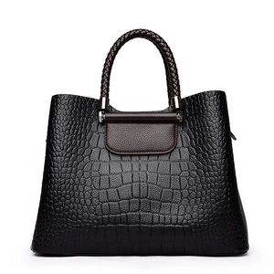 Sac à main noir motif crocodile avec poignées tressées marron et détails argentés