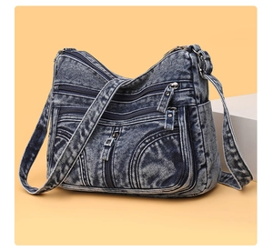 Dettaglio della borsa a tracolla in denim lavato con cerniere argentate a strati multipli