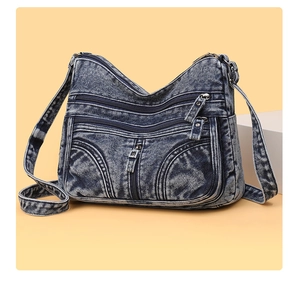 Dettaglio della borsa a tracolla in denim lavato con tasche multiple e trama del tessuto