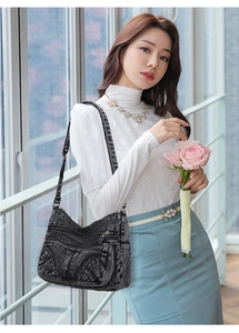Borsa a tracolla in denim lavato con tasche con zip mostrata in stile lifestyle