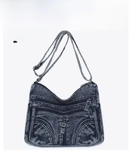 Dettaglio della borsa a tracolla in denim blu con tasche multiple e cinturino regolabile