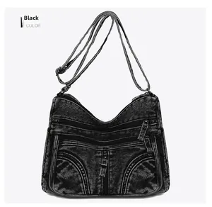 Vista frontale della borsa a tracolla vintage in denim nero con cerniere multiple