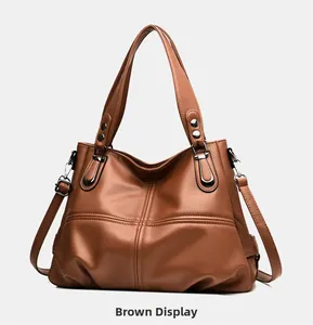 Dettaglio della borsa tote in pelle marrone con cuciture a croce e rivetti metallici