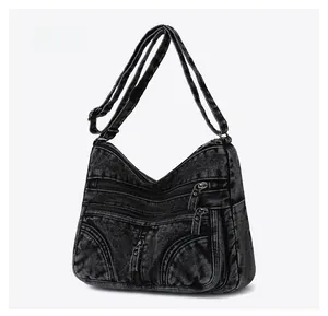 Vista laterale della borsa a tracolla in denim nero lavato con cerniere metalliche multiple