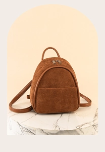Macro shot of brown corduroy mini backpack with faux leather trim on a white marble stand