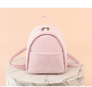 Detail of pink corduroy mini backpack with metal double zippers on marble pedestal