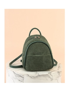 Macro detail of dark green corduroy fabric texture on a stylish mini backpack