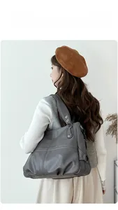Dettaglio della borsa tote in pelle grigio scuro con cuciture geometriche e borchie sul manico