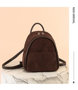 Detail view of brown corduroy mini backpack with double zipper on marble display stand