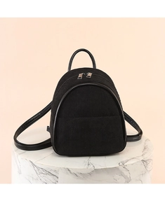Detail of black corduroy mini backpack with faux leather trim on a marble pedestal