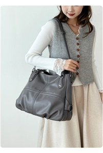 Dettaglio della borsa tote grigio scuro con texture in pelle morbida e tracolla regolabile