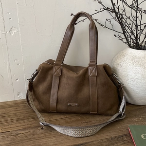 Large dark brown suede Boston tote bag with jacquard strap on a rustic wood table