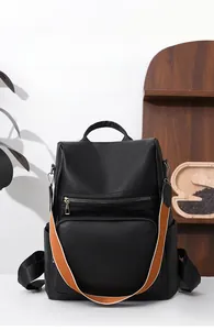 Close-up of black PU leather backpack with an extra orange striped woven shoulder strap