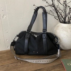 Large black nylon tote bag with leather handles and colorful geometric woven strap