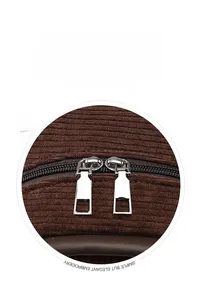 Detail view of smooth silver metal double zippers on brown corduroy backpack fabric