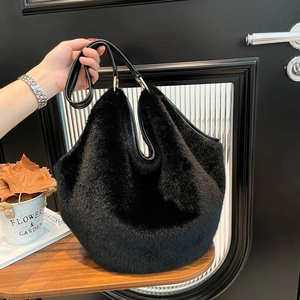 Large black plush faux fur tote bag with leather handles and gold metal ring details